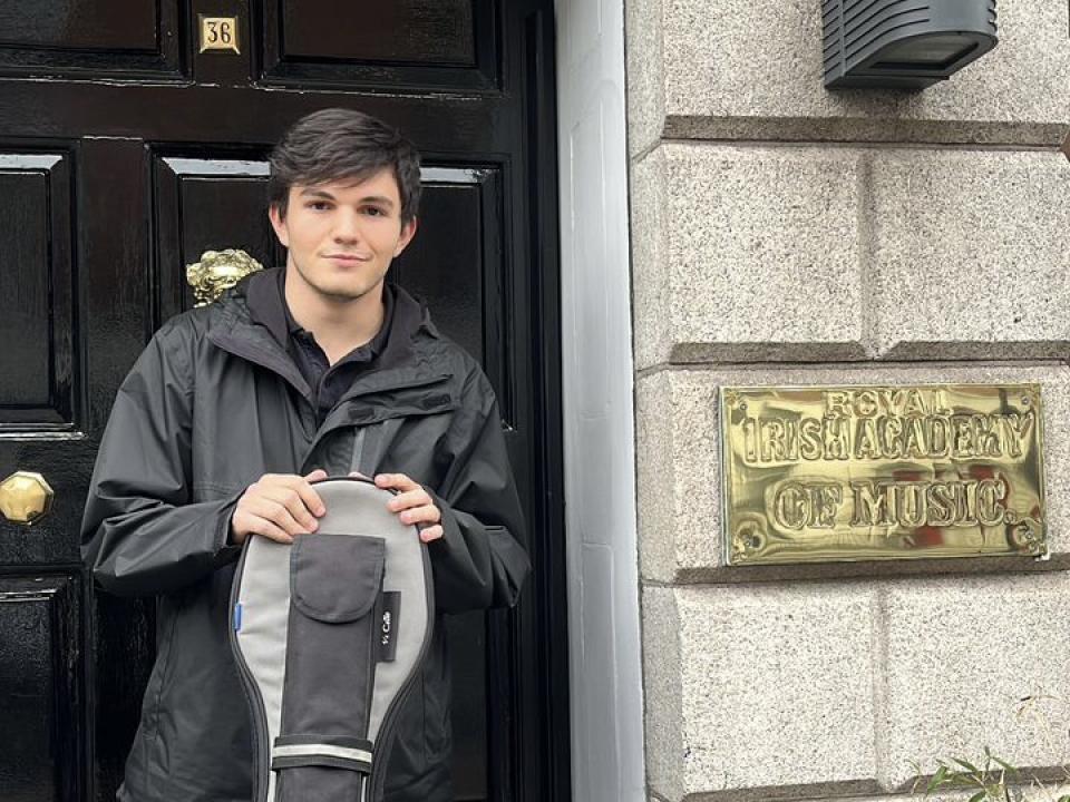 Cellist Andrés Vaccaro stands outside the front of the RIAM building holding his cello