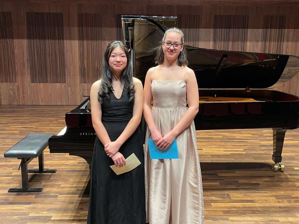 Two girls standing and smiling on stage with envelopes in their hands
