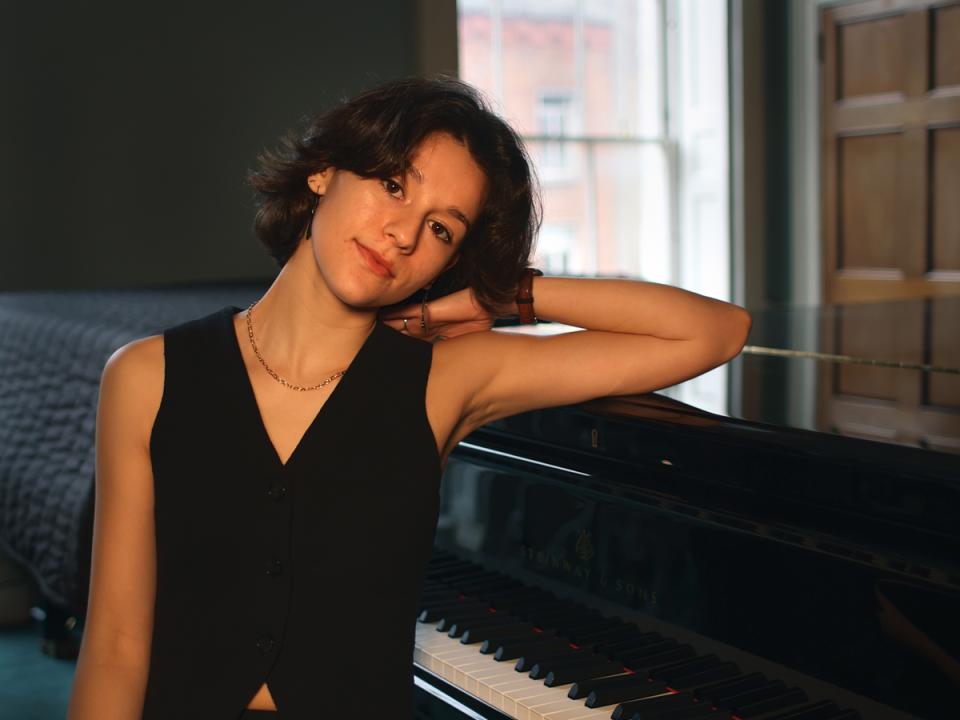 Sofia Féria leaning on a piano 
