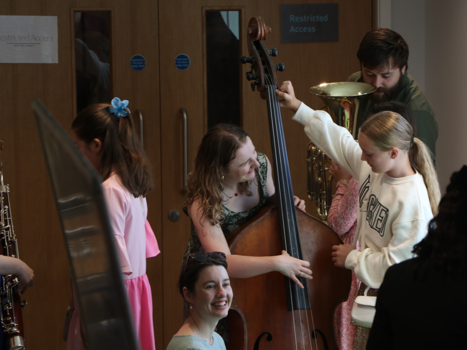 Image of tutors showing children the instruments of the orchestra